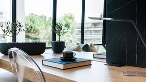 Um espaço de trabalho moderno com uma mesa de madeira, duas plantas em vasos, um laptop e uma chávena.