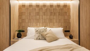 Camera da letto moderna con testiera in legno, letto rifatto con cura e comodini decorati.