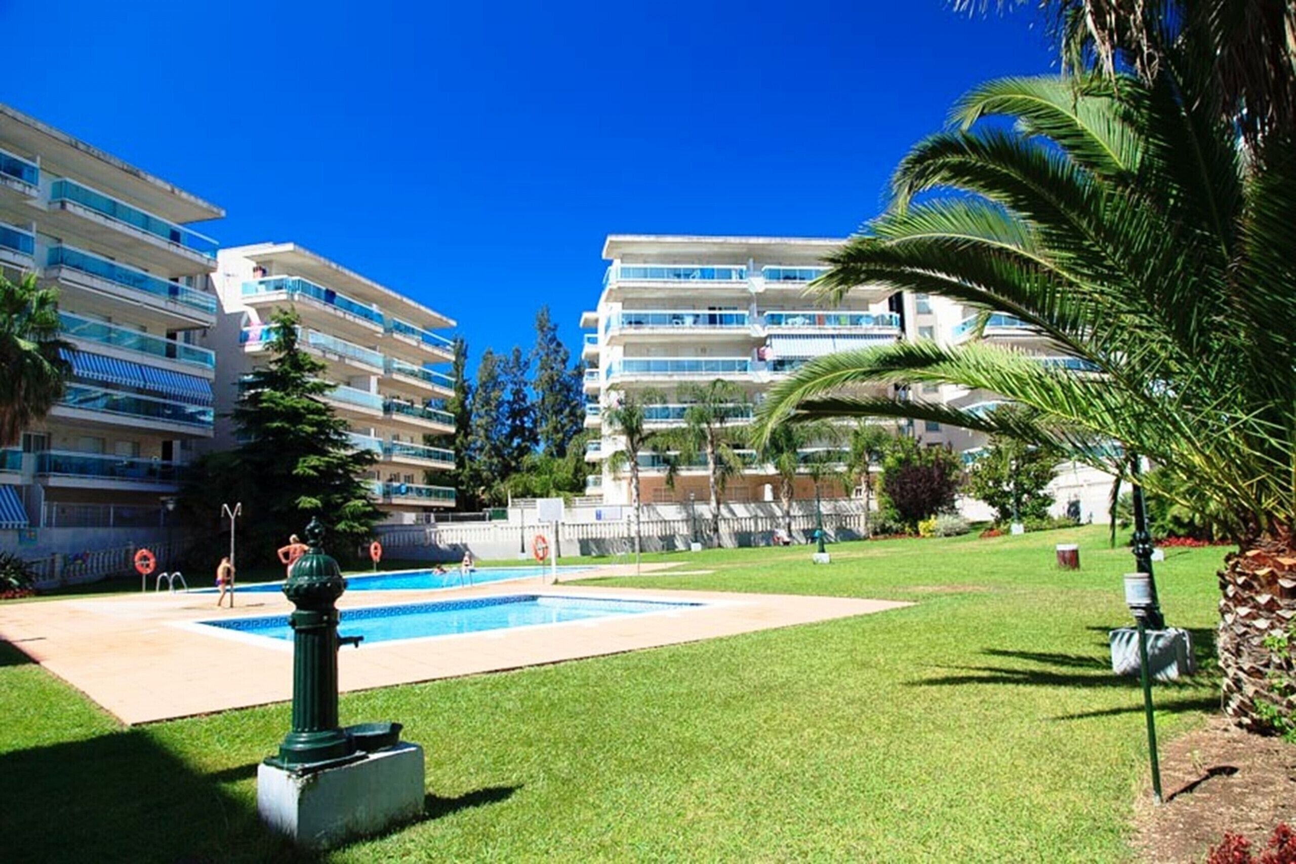 Ein Hotel mit mehreren Balkonen, einem Schwimmbad und üppiger Bepflanzung.