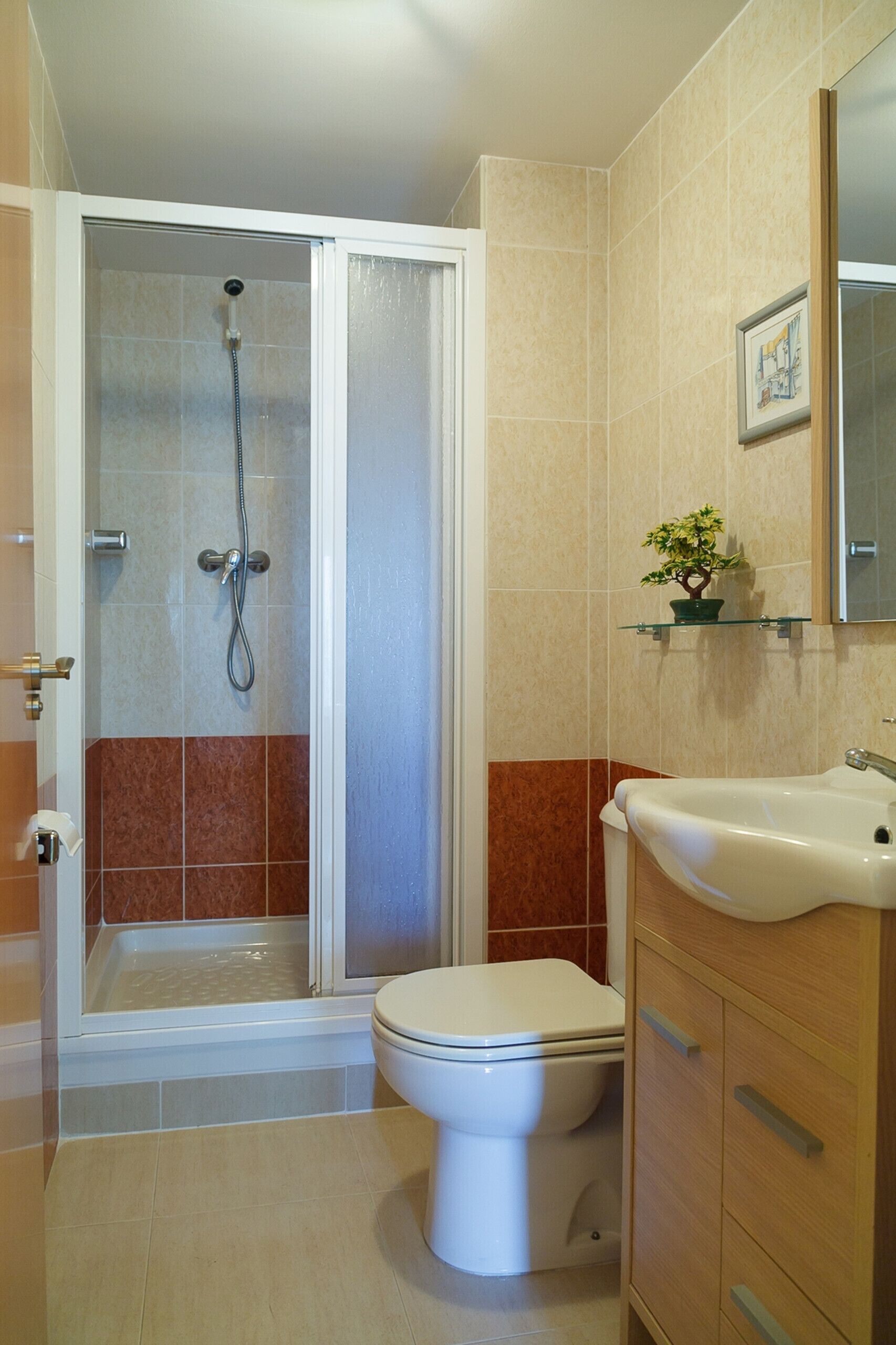 A bathroom with a shower enclosure, a toilet, and a sink.