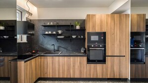 A modern kitchen with wooden cabinetry, a black countertop, a built-in oven, and a microwave.