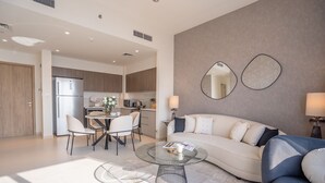 A modern living room with a sofa, coffee table, and dining area. - Nasma Luxury Stays - Dubai Hills (Dubai)