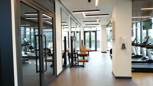 A modern gym with exercise equipment, large windows, and a clean, spacious layout. - Nasma Luxury Stays - Dubai Hills (Dubai)