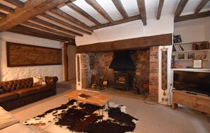 Una sala de estar acogedora con chimenea, sofá de cuero y alfombra de cuero de vaca.