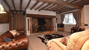 A cozy living room with a fireplace, leather sofas, and a cowhide rug. - Oak House (Rye)