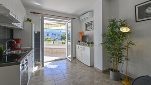 A modern kitchen with a sliding glass door leading to a balcony, a potted plant, and a floor lamp. - Apartments Adela II (Novalja)