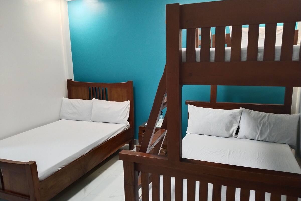 Zwei hölzerne Betten mit weißer Bettwäsche in einem Zimmer mit blauen Wänden.