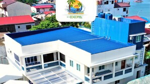 Un hôtel moderne avec un toit bleu, de nombreux balcons et un espace de restauration extérieur couvert.