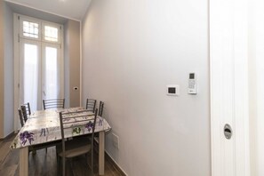 A dining area with a table, chairs, a door with a keypad, and a window. - Cozy and functional apartment perfect to accommodate 4 people and located in the heart of the Lingotto area, ideal for work, tourism and study. We are just a few minutes far from the hospital area (Molinette, San Lazzaro Dermatological Hospital, Regina M (Torino)