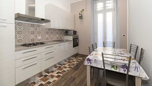 A compact kitchen with white cabinets, a gas stove, a microwave, and a patterned backsplash. - Cozy and functional apartment perfect to accommodate 4 people and located in the heart of the Lingotto area, ideal for work, tourism and study. We are just a few minutes far from the hospital area (Molinette, San Lazzaro Dermatological Hospital, Regina M (Torino)
