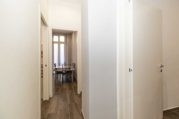 A hallway with a dining area at the end, featuring a table and chairs. - Cozy and functional apartment perfect to accommodate 4 people and located in the heart of the Lingotto area, ideal for work, tourism and study. We are just a few minutes far from the hospital area (Molinette, San Lazzaro Dermatological Hospital, Regina M (Torino)