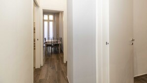 A hallway with a dining area at the end, featuring a table and chairs. - Cozy and functional apartment perfect to accommodate 4 people and located in the heart of the Lingotto area, ideal for work, tourism and study. We are just a few minutes far from the hospital area (Molinette, San Lazzaro Dermatological Hospital, Regina M (Torino)