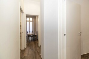 Ein Flur, am Ende befindet sich eine Essecke mit Tisch und Stühlen.