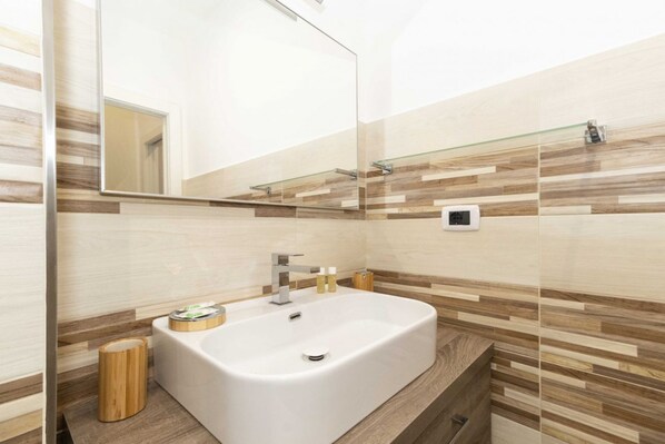 Un baño moderno con un lavamanos rectangular grande, un espejo y un mueble de tocador de madera.