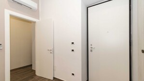 A hallway with two white doors, a wooden floor, and an air conditioning unit on the wall. - Cozy and functional apartment perfect to accommodate 4 people and located in the heart of the Lingotto area, ideal for work, tourism and study. We are just a few minutes far from the hospital area (Molinette, San Lazzaro Dermatological Hospital, Regina M (Torino)