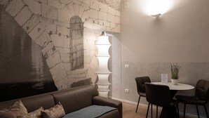 Een moderne kamer met een stenen muur, een bruine leren bank, een witte vloerlamp en een ronde tafel met stoelen.