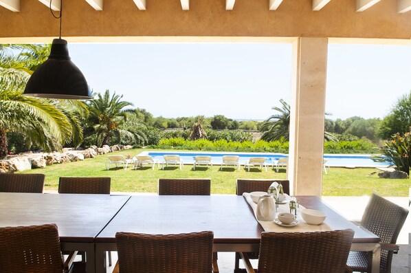 An outdoor dining area with a view of a swimming pool and lush greenery.