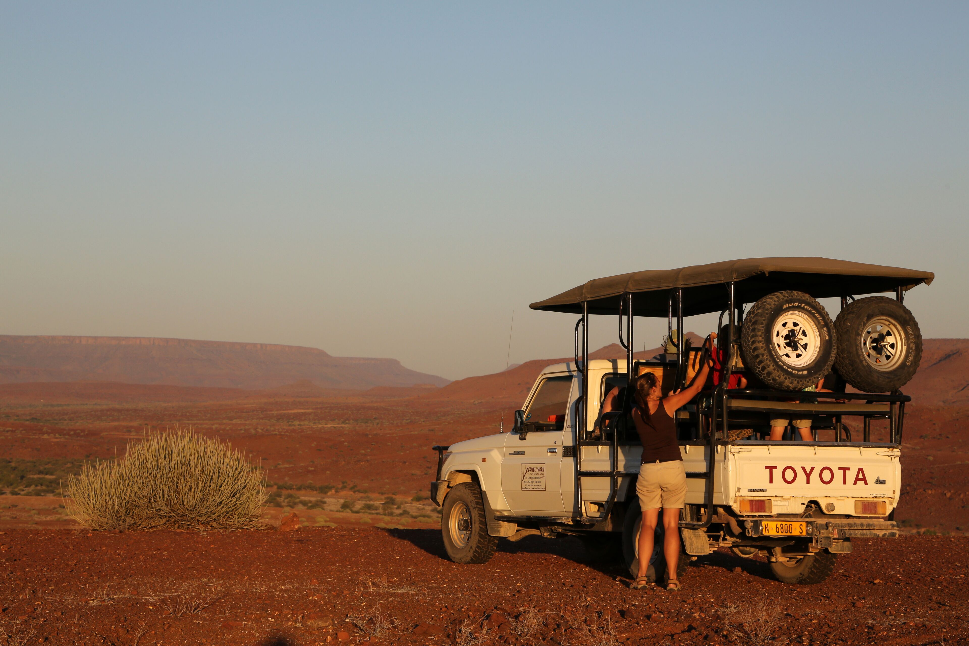 A Toyota off-road vehicle parked in a desert landscape with a person standing beside it.