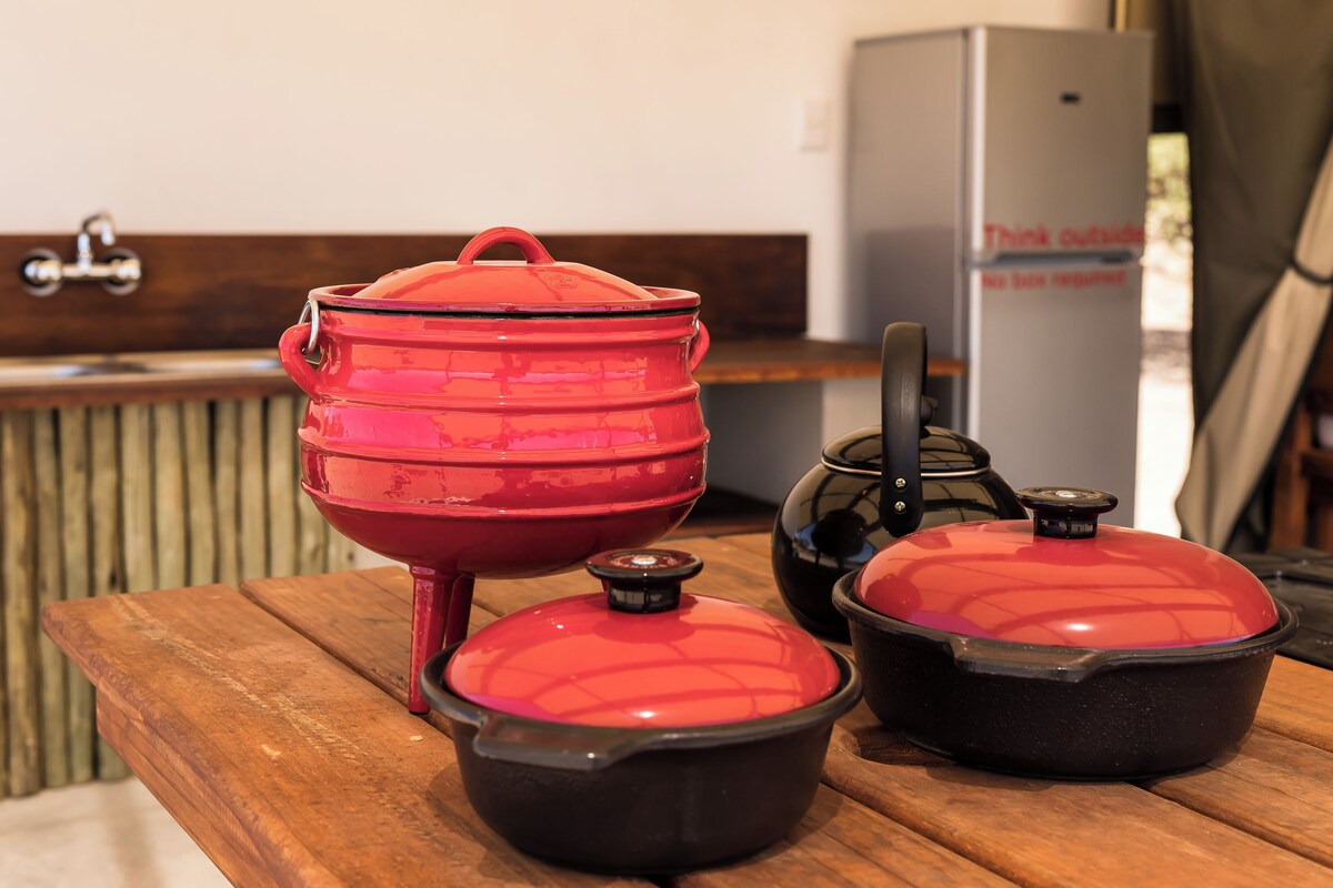 A kitchen with a wooden countertop, a red pot, and a black pot on it.