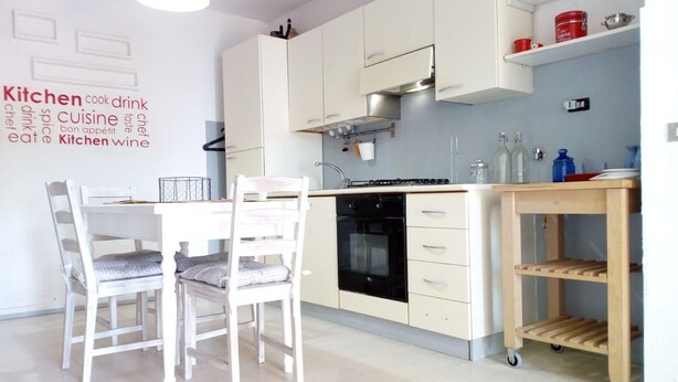 A modern kitchen with white cabinetry, a black oven, and a wooden island with a sink. - Casa Sprizze (Portoferraio)