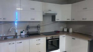 A modern kitchen with white cabinets, a stainless steel sink, a built-in oven, and a black countertop. - Los Gigantes, Fantastic 1 Room, balcony (Acantilados de Los Gigantes)