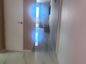 A hallway with a door, a window, and a light fixture.