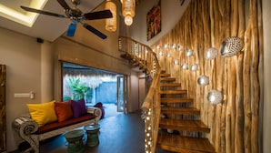 Un intérieur moderne avec un escalier en bois, un canapé agrémenté de coussins colorés et un ventilateur de plafond.