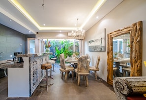 A modern kitchen with a bar area, wooden chairs, and a dining table.