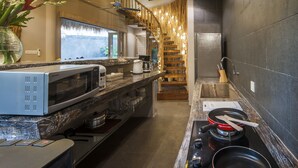 Une cuisine moderne équipée d’un four à micro-ondes, d’une cuisinière et d’un évier intégrés. Un escalier en bois mène à un balcon offrant une vue sur l’extérieur.