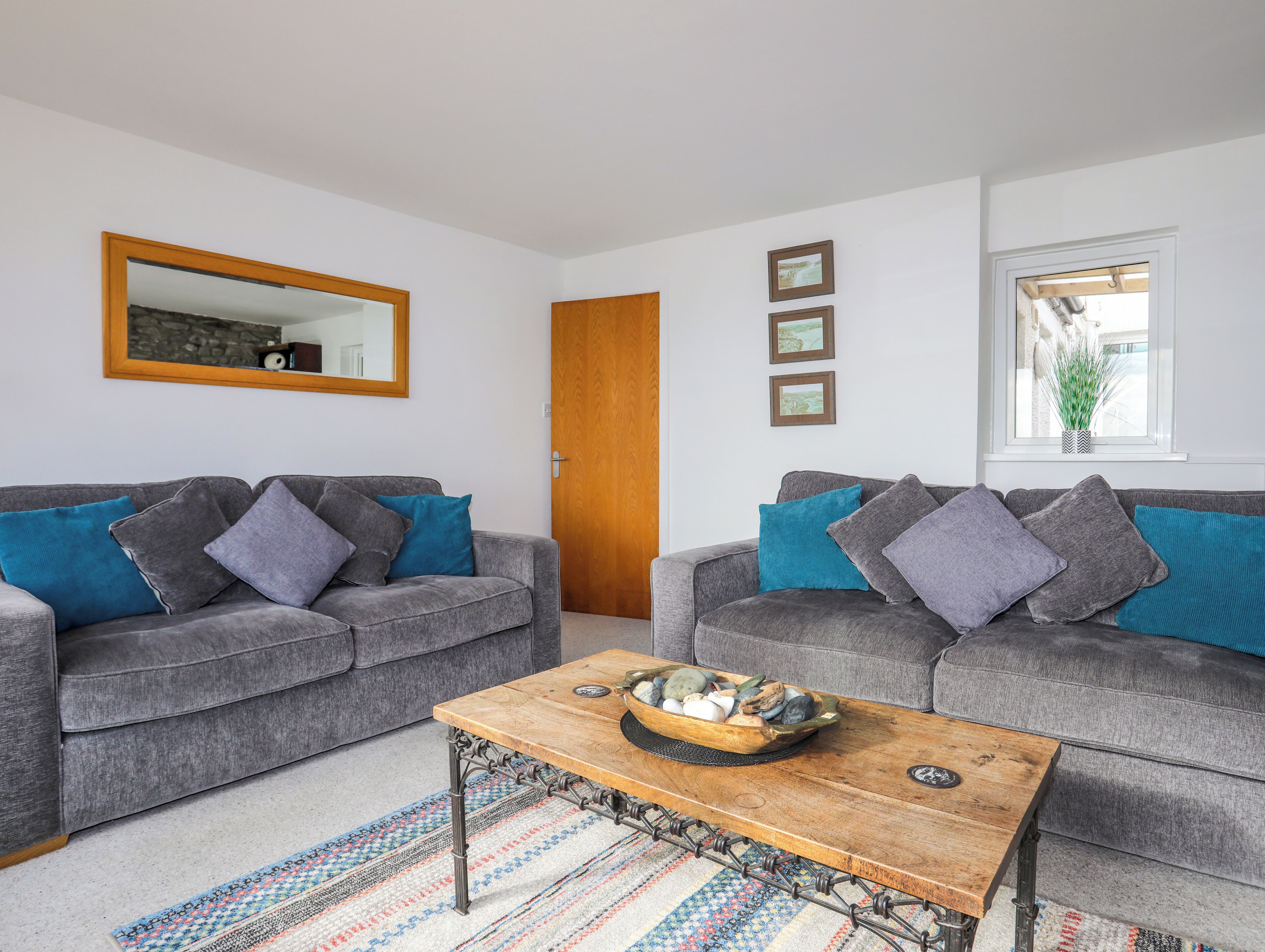 A living room with two grey sofas, a wooden coffee table, and a patterned rug.