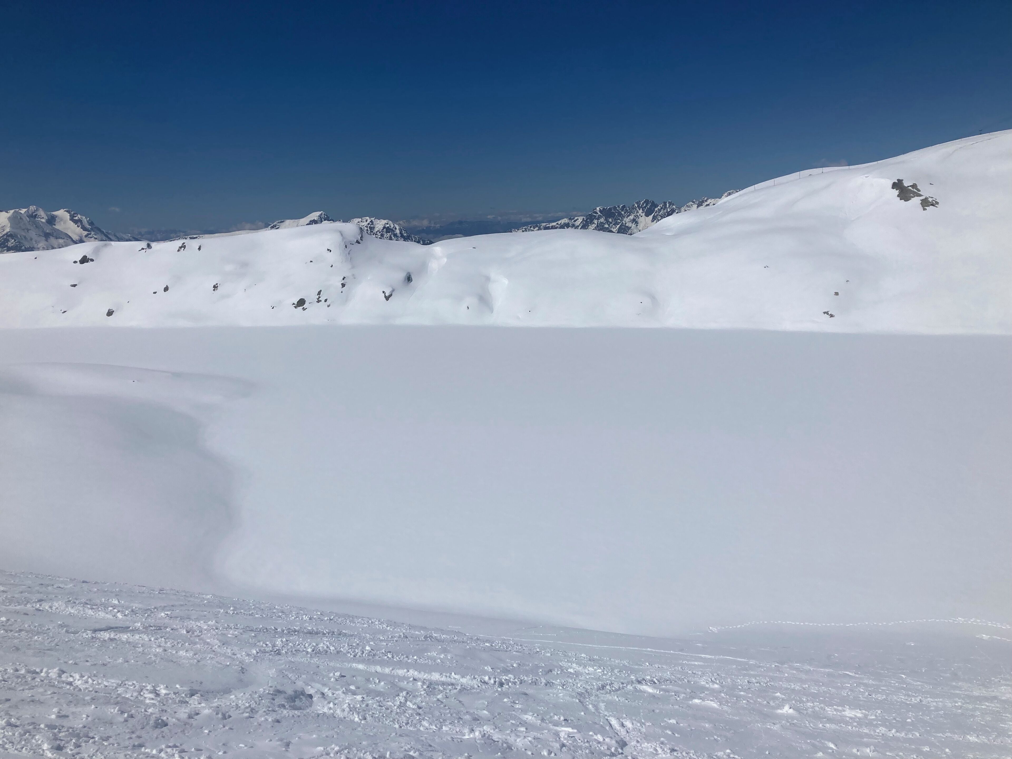 A snow-covered landscape with a clear sky and distant mountains.