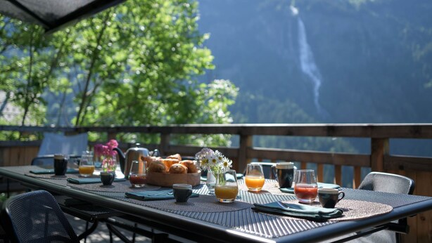A breakfast table set outdoors with a mountain view, including a waterfall. - "Refuge des Sens", Chalet "Quiétude" (Vaujany)