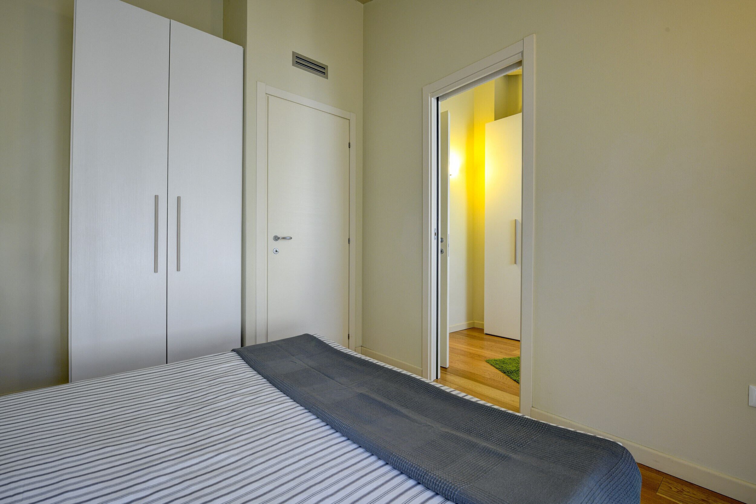 A bedroom with a bed, a wardrobe, and a door leading to another room.