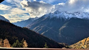 Eine Berglandschaft mit schneebedeckten Gipfeln und einem bewaldeten Tal.