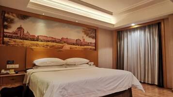 Una habitación de hotel con una cama grande, una mesita de noche con teléfono, un cuadro de un edificio en la pared y una ventana con cortinas.