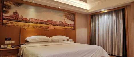 A hotel room with a large bed, a nightstand with a phone, a painting of a building on the wall, and a window with curtains.