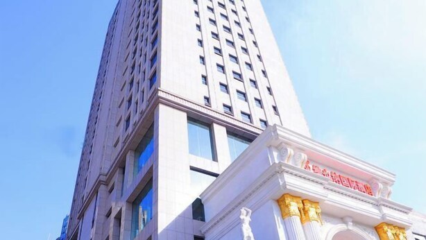 A tall building with a classical architectural style, featuring a prominent entrance with columns and a statue. - Vienna International Hotel (Tianmen Wanda Plaza Donghu Branch) (Tianmen)