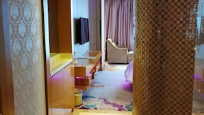 A hotel room with a bed, a TV mounted on the wall, a small seating area, and a patterned carpet. - Vienna International Hotel (Tianmen Wanda Plaza Donghu Branch) (Tianmen)