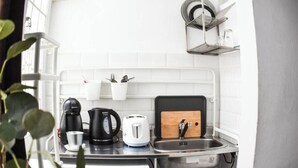 Cozinha compacta com pia, cafeteira, chaleira e torradeira.