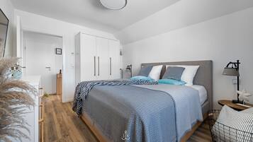 A modern bedroom with a bed, bedside tables, and a wardrobe.