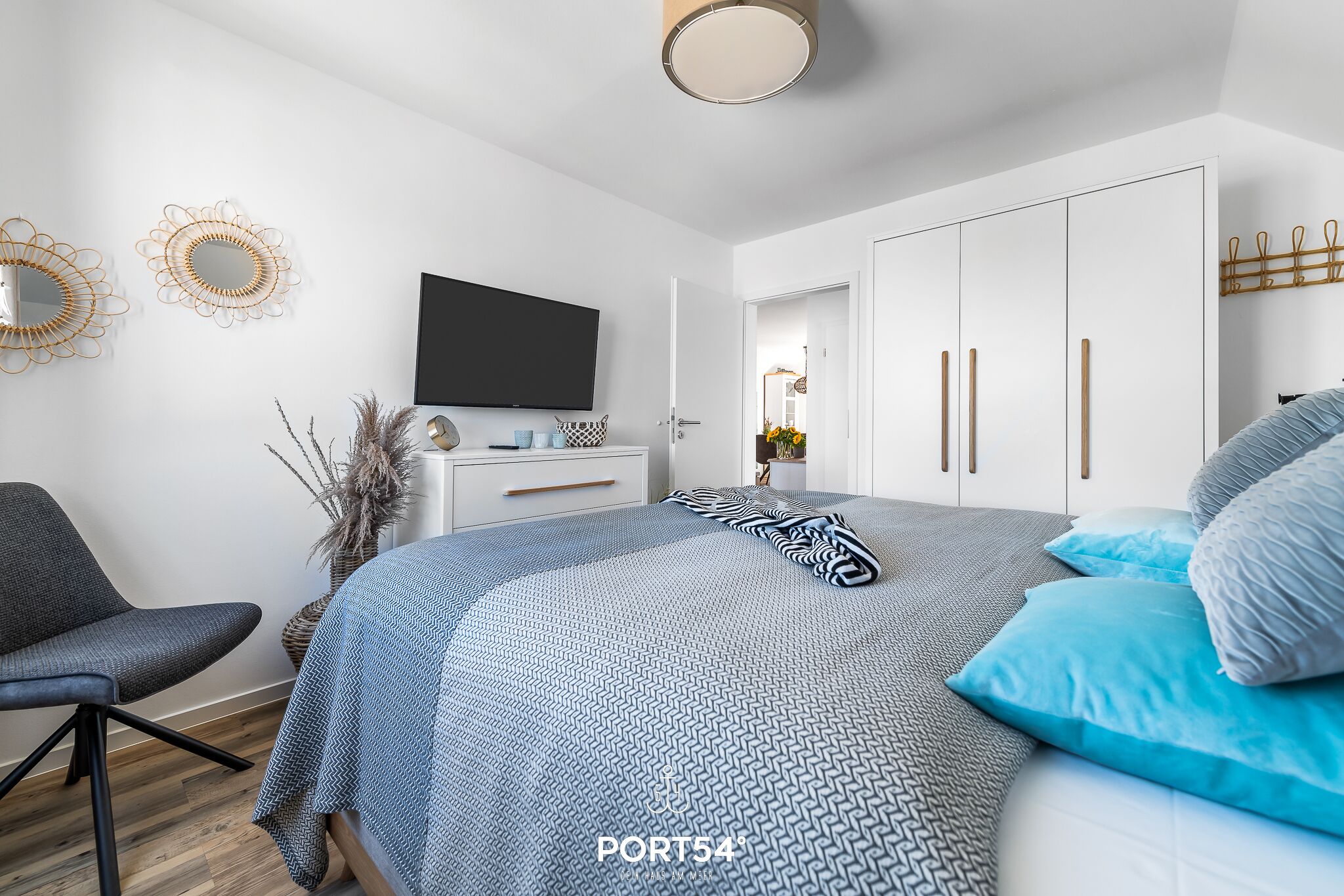 Een moderne slaapkamer met een bed, een televisie, een kledingkast en een stoel.