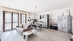 Un apartamento moderno con sala de estar, comedor, cocina y un balcón con ventanales grandes.