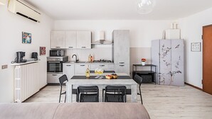 Una cocina moderna con comedor, que cuenta con una isla central, electrodomésticos integrados y un refrigerador grande con paneles decorativos.