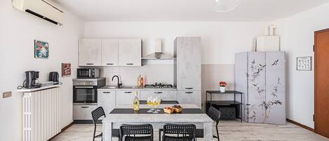 Een moderne keuken met een eethoek, met een centraal kookeiland, inbouwapparatuur en een grote koelkast met decoratieve panelen.