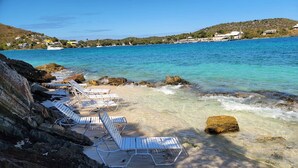 Une plage avec des chaises longues et une côte rocheuse.