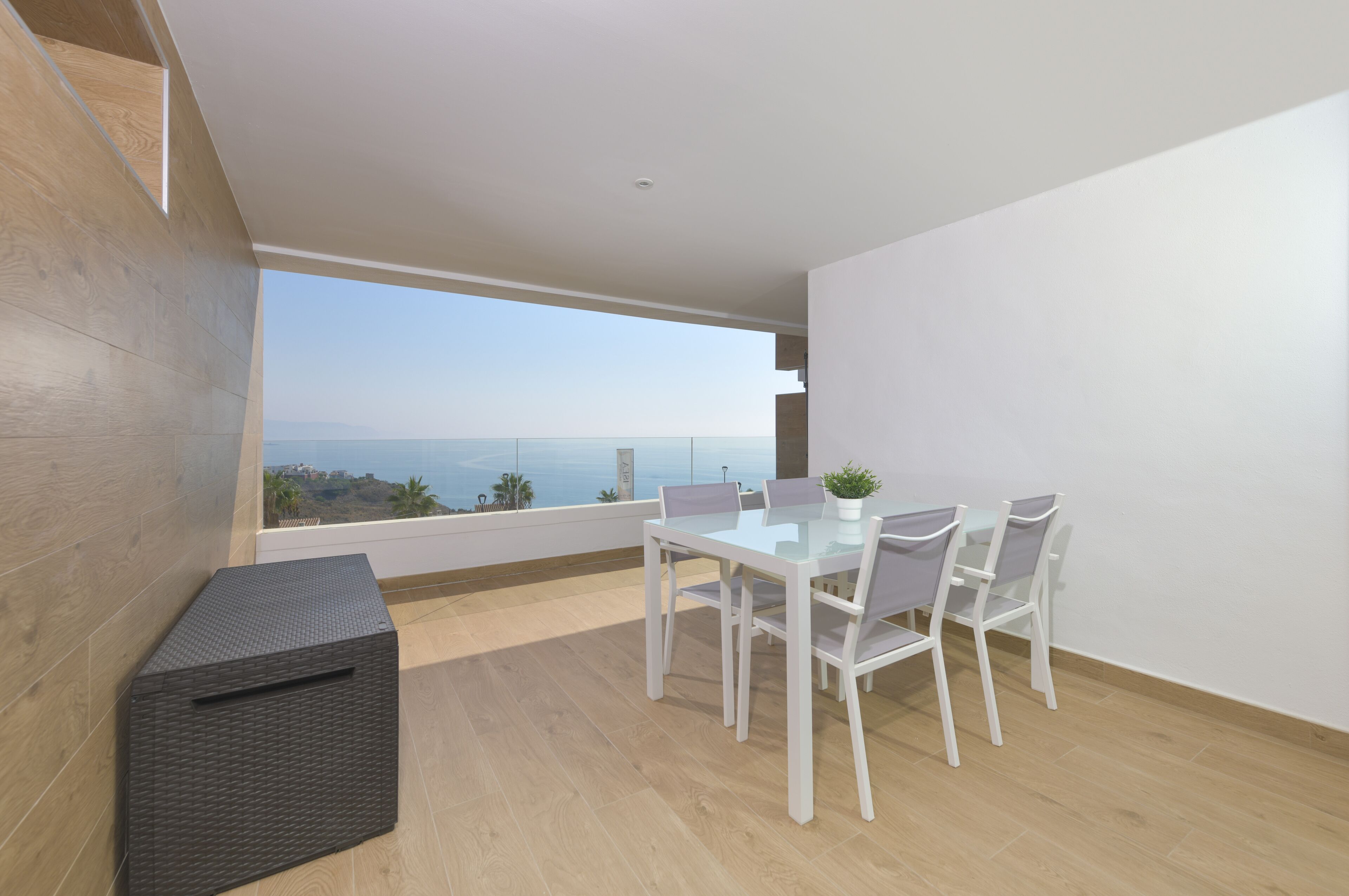 A modern dining area with a table and chairs, a small plant, and a view of the sea.