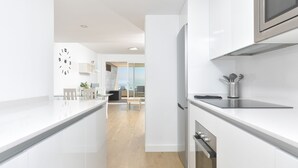 A modern kitchen with white cabinetry, a stainless steel refrigerator, and a built-in microwave.