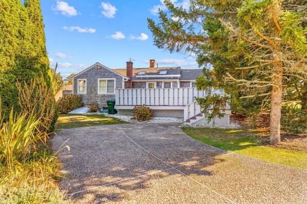 A house with a gravel driveway, a wooden fence, and a small garden area.