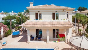 A two-story house with a tiled roof, a balcony with a red awning, and a pool in the foreground. - Villa Hanna  3 Bedrooms (Protaras)