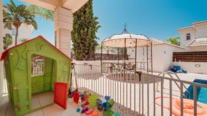 A children's play area with a green playhouse and a poolside setting. - Villa Hanna  3 Bedrooms (Protaras)